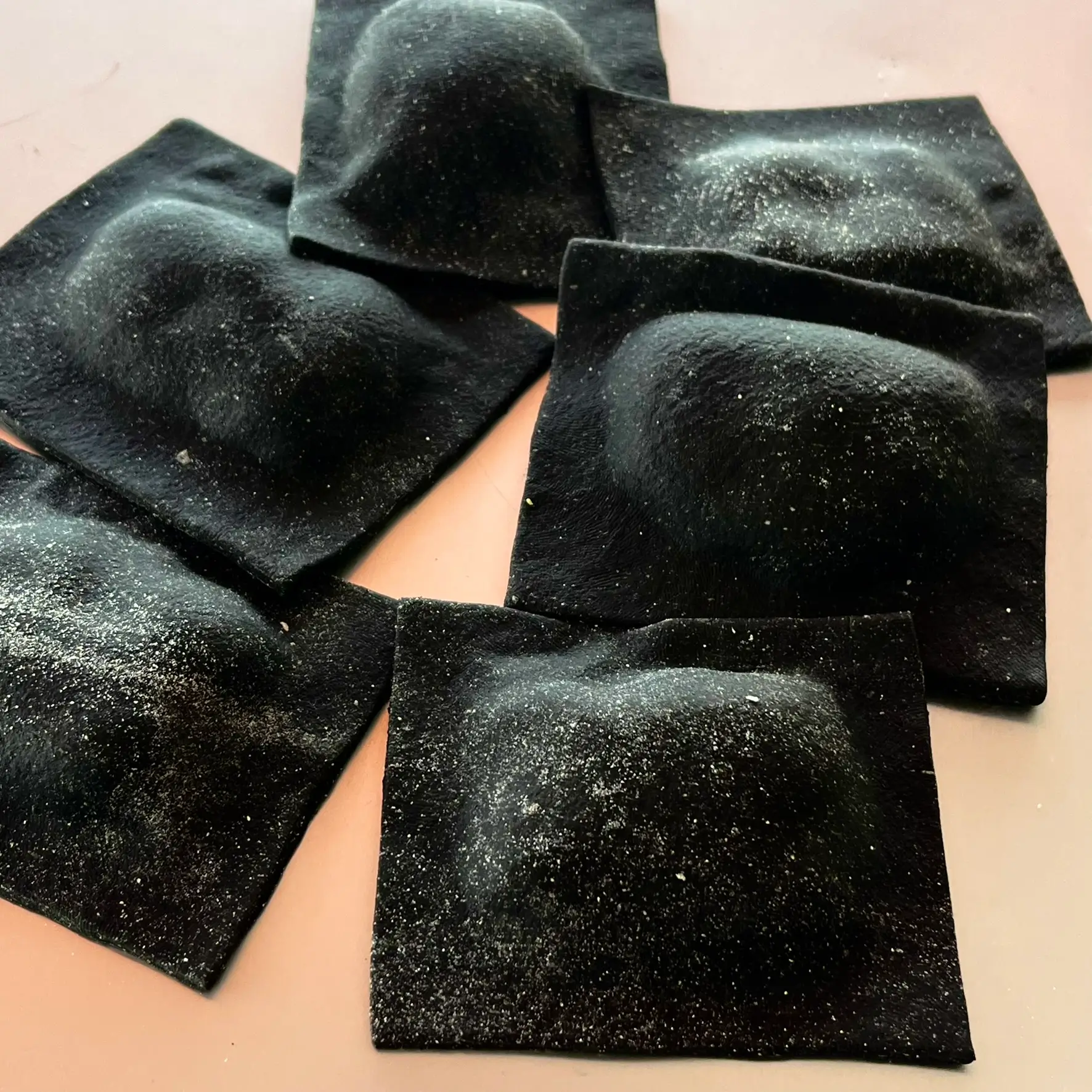 Sveži ročno izdelani črni ravioli s sipinim črnilom, polnjeni s gamberi in maskarponejem.