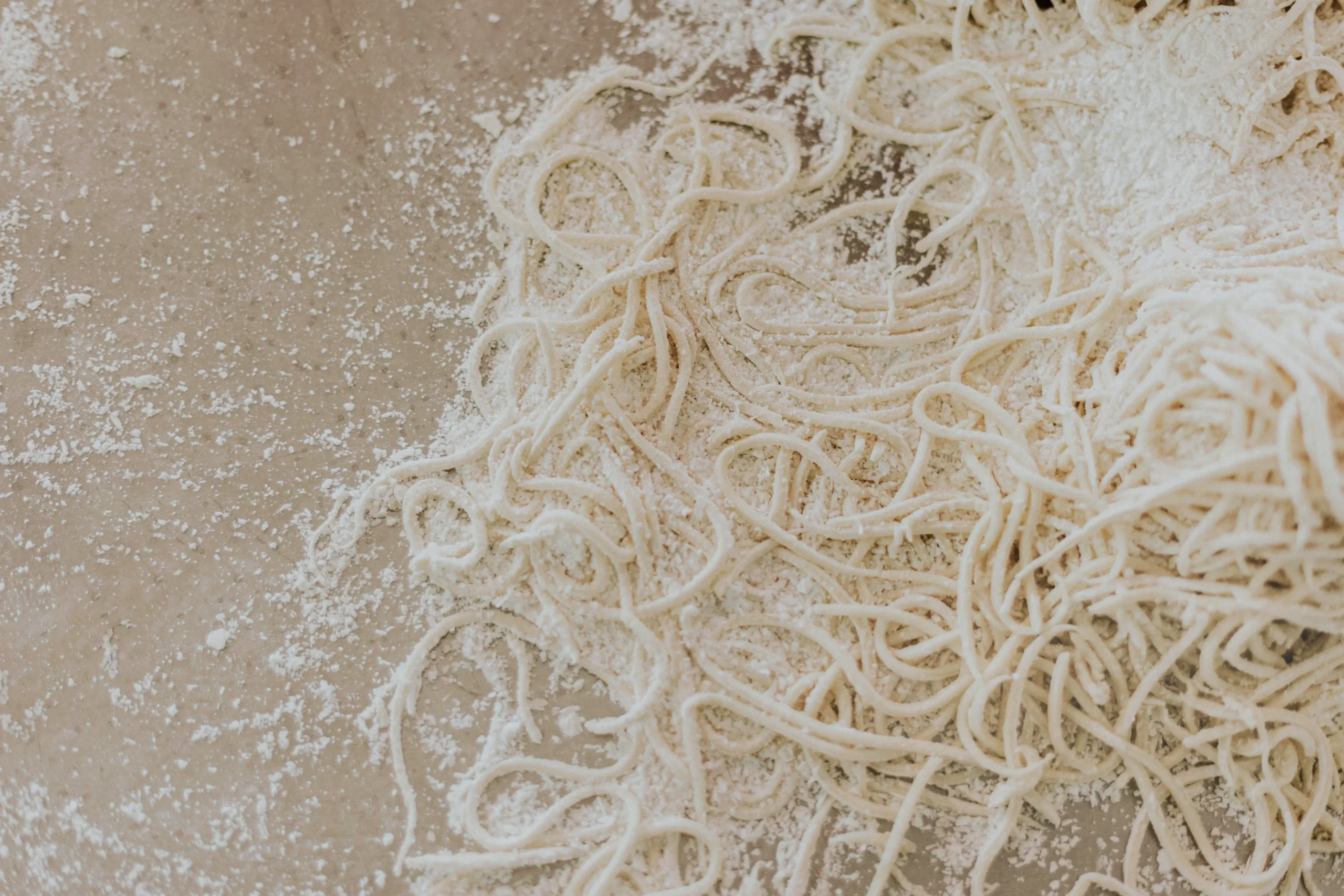 Sveži domači ročno izdelani tanki rezanci ali špageti po pomokani mizi.