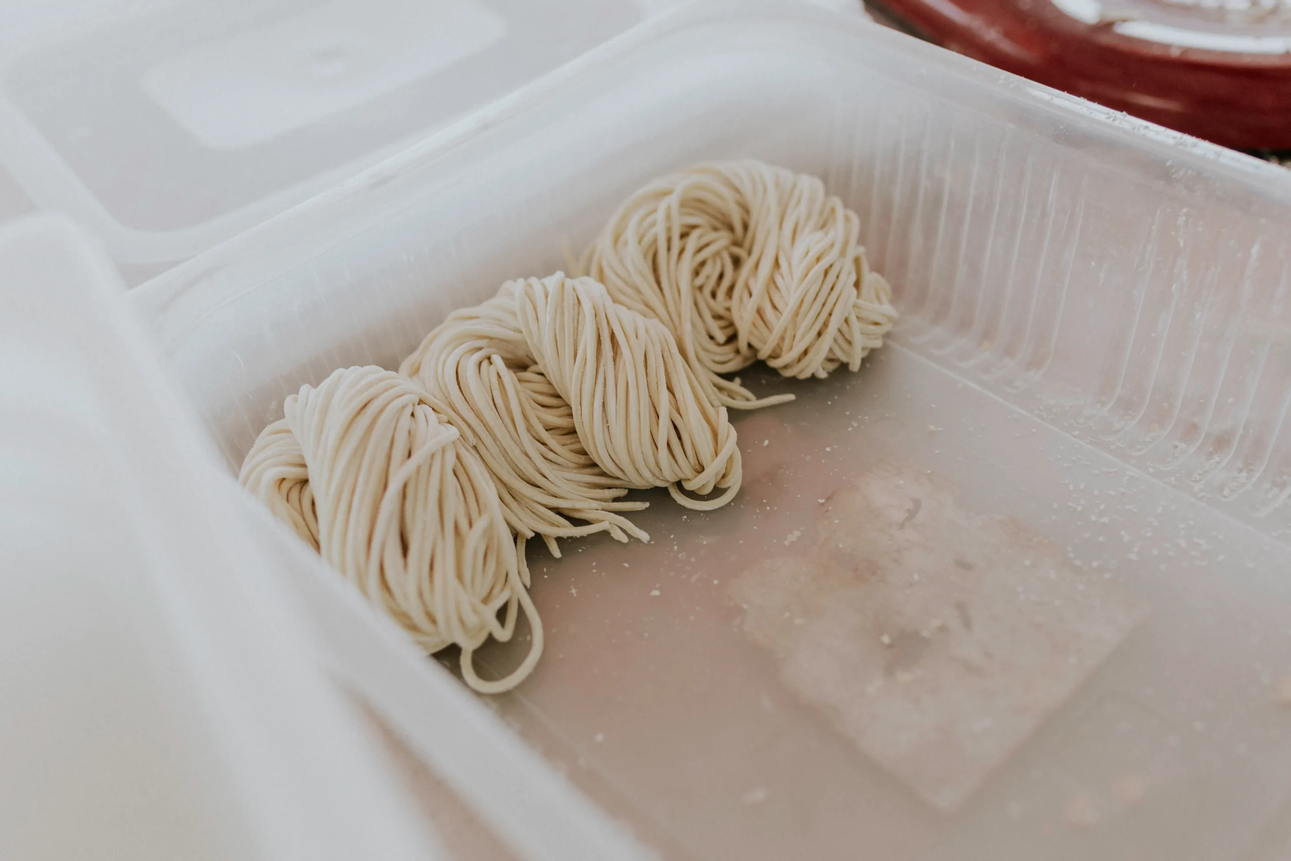 Sveži domači ročno izdelani tanki rezanci ali špageti zviti v klopčičih.
